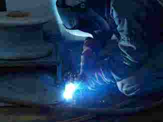 A person welding where the light from the welding is seen