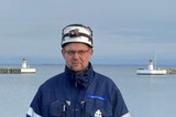 Man in blue jacket and white helmet in front of two lighthouses
