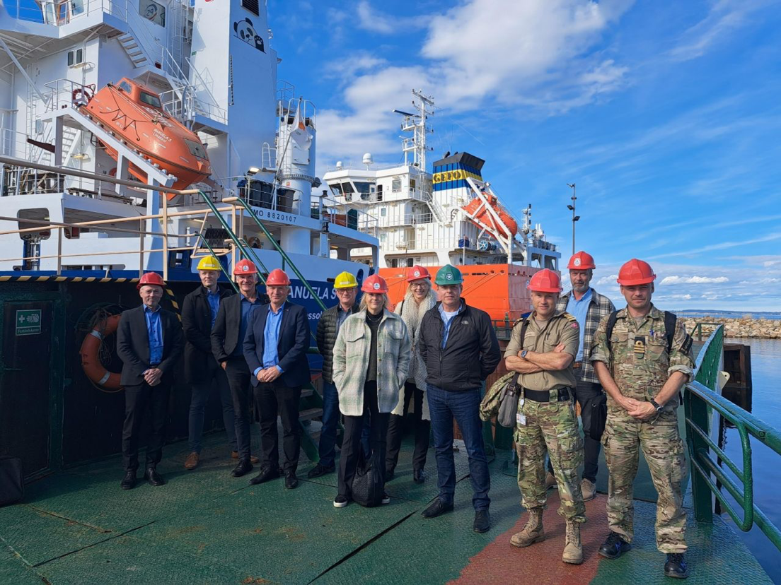 Group photo of 11 persons in front of two vessels