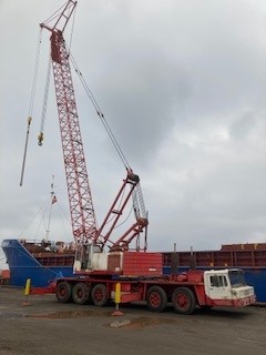Red mobile crane seen in front of a vessel