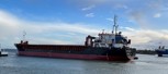 Black and red dry-cargo vessel leaving port after dry-dock